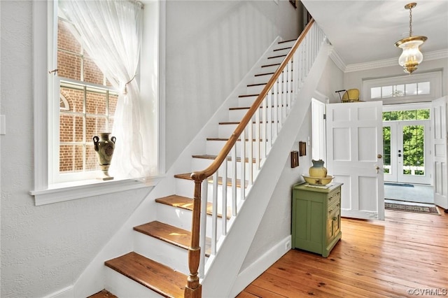 entrance foyer featuring ornamental molding, light wood-style floors, baseboards, stairs, and a textured wall