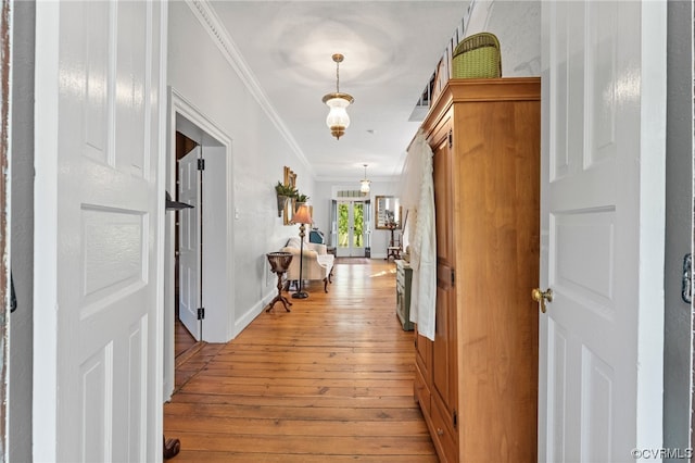 hall featuring baseboards, light wood-style flooring, and crown molding