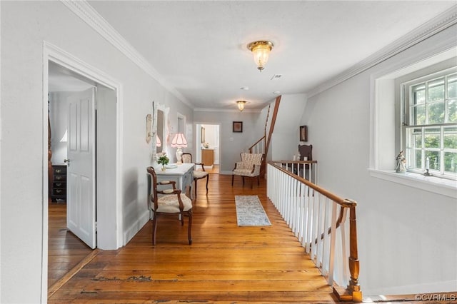 corridor featuring light wood-type flooring, baseboards, ornamental molding, and stairway