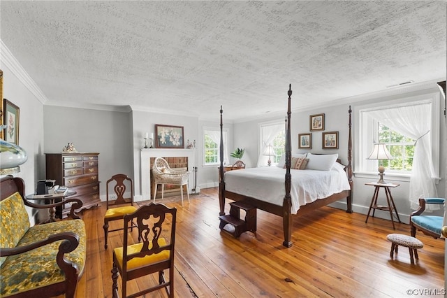 bedroom with multiple windows, a textured ceiling, crown molding, and hardwood / wood-style flooring