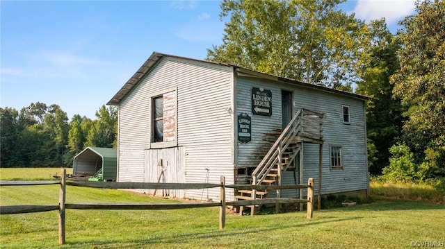 rear view of property with a yard, fence, a carport, and stairway