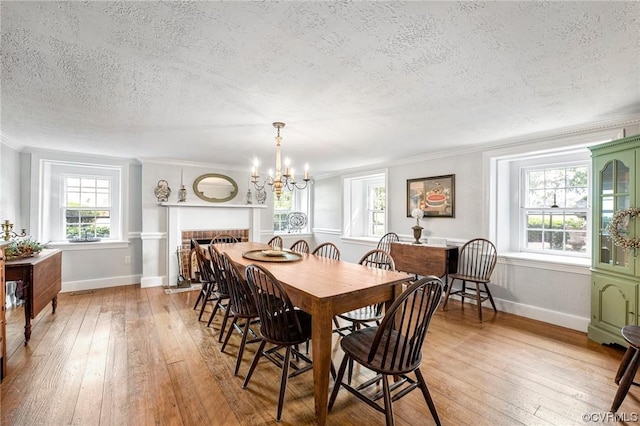 dining area featuring light wood-type flooring, baseboards, and a notable chandelier