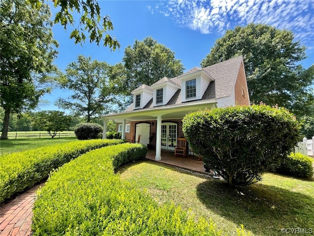 cape cod home featuring brick siding, french doors, a front lawn, and fence