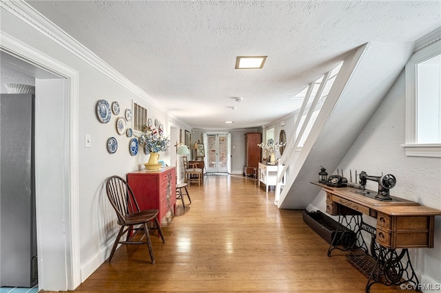 hallway with ornamental molding, wood finished floors, baseboards, and a textured ceiling