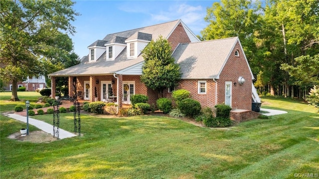 new england style home featuring a front lawn, brick siding, and roof with shingles