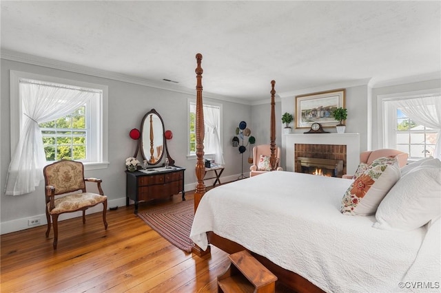 bedroom with multiple windows, ornamental molding, and light wood finished floors