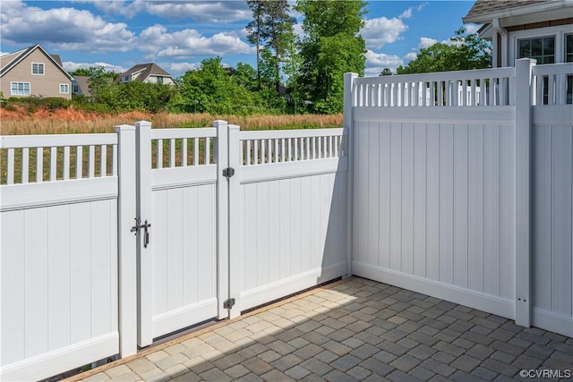 view of gate with fence and a patio