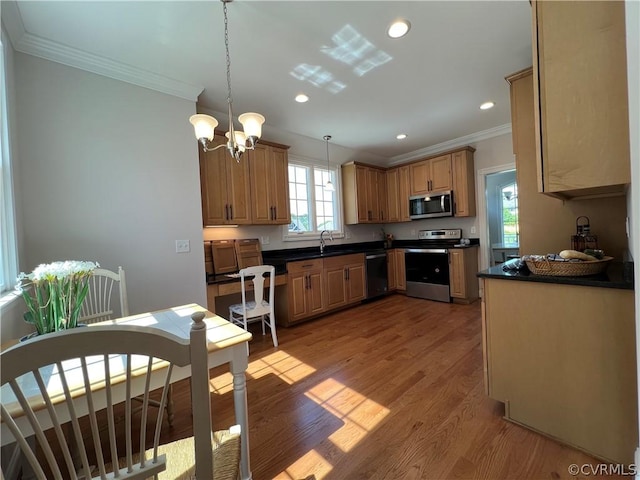 kitchen with light wood finished floors, dark countertops, appliances with stainless steel finishes, crown molding, and a sink