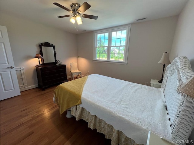 bedroom featuring ceiling fan, wood finished floors, visible vents, and baseboards