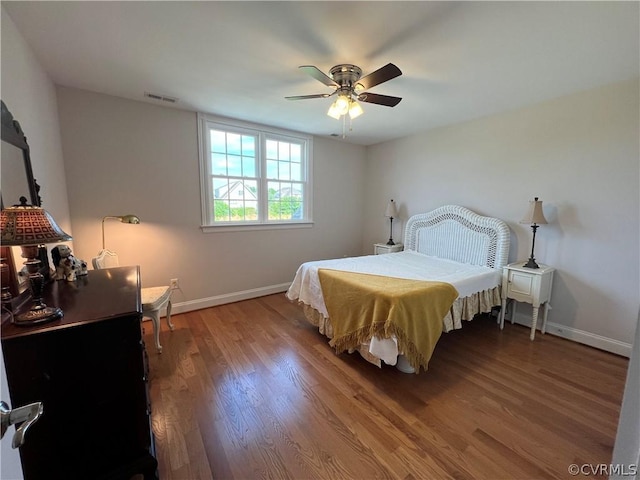 bedroom featuring a ceiling fan, baseboards, visible vents, and wood finished floors