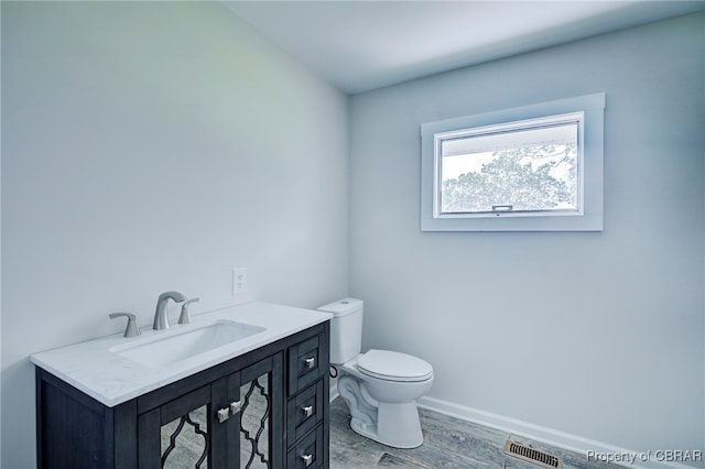 bathroom with hardwood / wood-style floors, vanity, and toilet