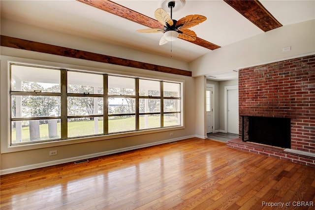 unfurnished living room featuring lofted ceiling with beams, light hardwood / wood-style floors, ceiling fan, and a fireplace