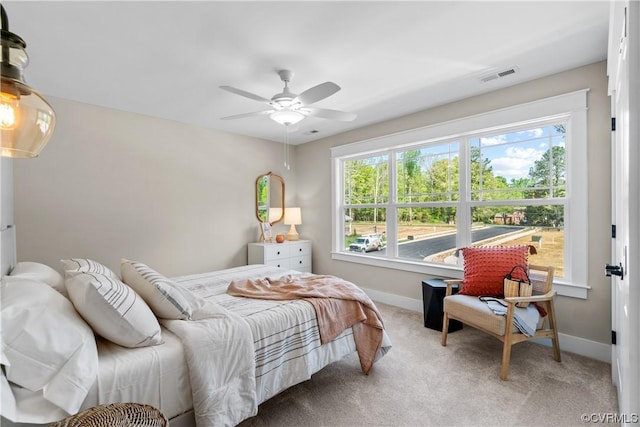 carpeted bedroom with visible vents, multiple windows, baseboards, and ceiling fan