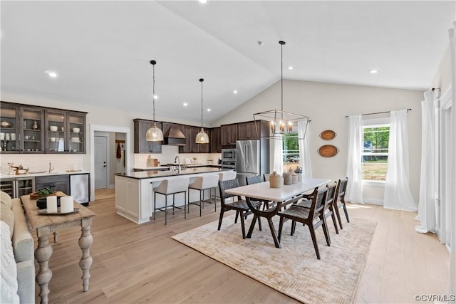 dining space with vaulted ceiling, recessed lighting, light wood-type flooring, and a chandelier