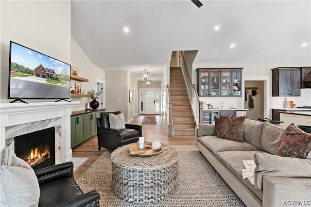 living room with stairway, recessed lighting, light wood-style floors, and a premium fireplace