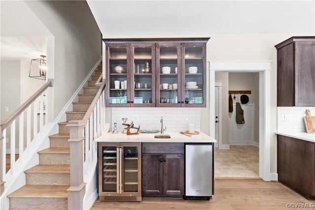 bar featuring tasteful backsplash, wine cooler, stairs, light wood-style flooring, and fridge