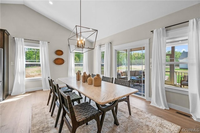 dining room with visible vents, baseboards, vaulted ceiling, light wood-style floors, and a notable chandelier