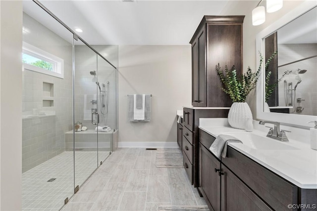 bathroom featuring vanity, baseboards, and a stall shower