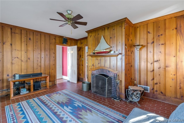 living room featuring wooden walls, ceiling fan, and a fireplace