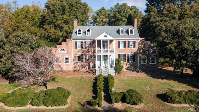 rear view of house featuring a balcony and a lawn