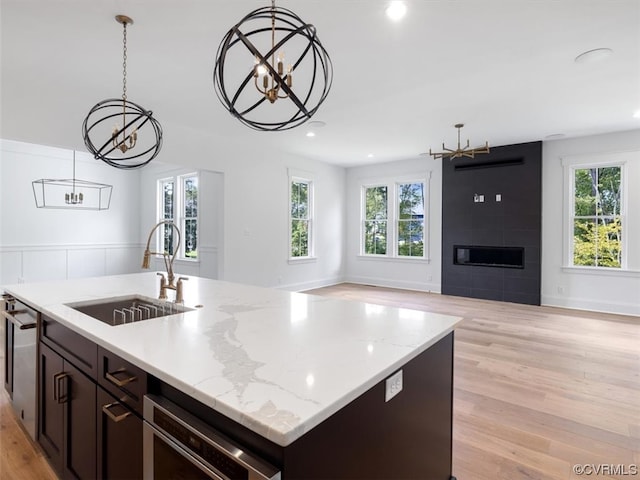 kitchen with pendant lighting, a fireplace, sink, and a healthy amount of sunlight