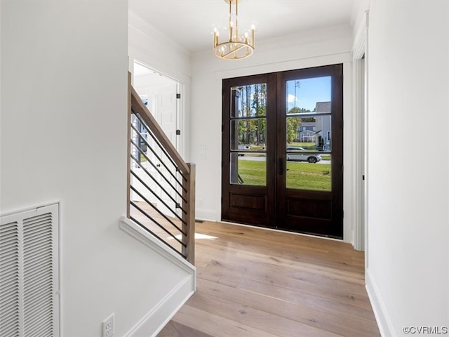 entryway with french doors, a chandelier, and light hardwood / wood-style floors