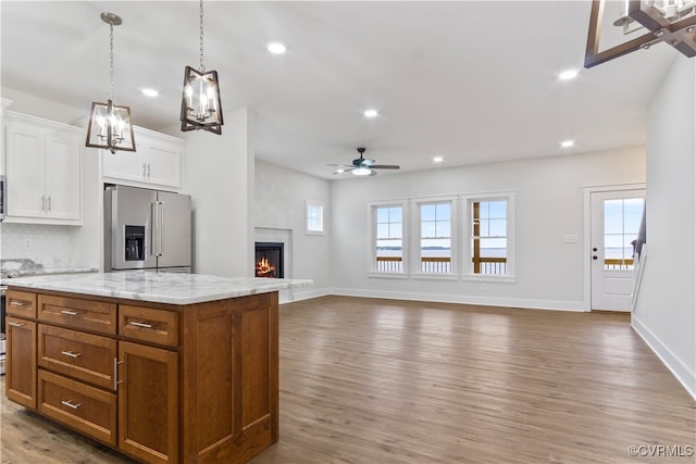 kitchen featuring ceiling fan with notable chandelier, a fireplace, a kitchen island, hardwood / wood-style flooring, and high end fridge