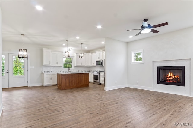 kitchen featuring pendant lighting, white cabinets, appliances with stainless steel finishes, a center island, and ceiling fan with notable chandelier