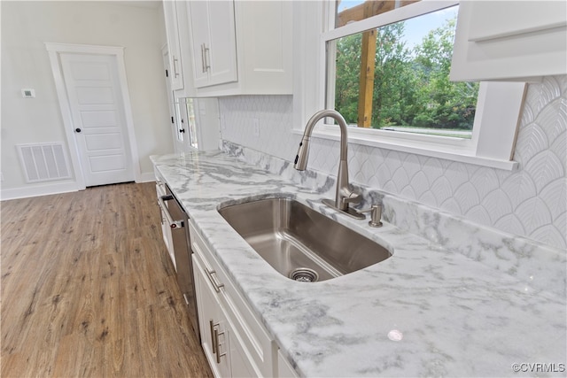 kitchen featuring light stone countertops, light wood-type flooring, sink, and white cabinetry