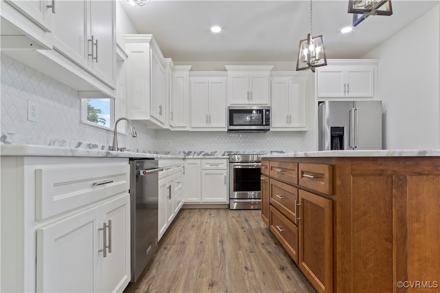 kitchen with hardwood / wood-style flooring, an inviting chandelier, stainless steel appliances, and white cabinets