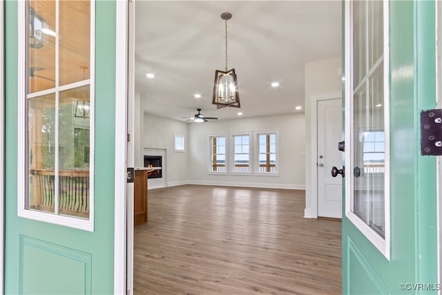 entryway featuring ceiling fan with notable chandelier and dark hardwood / wood-style flooring