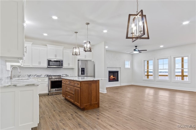 kitchen featuring light stone counters, stainless steel appliances, white cabinetry, and a kitchen island