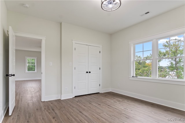 unfurnished bedroom with multiple windows, hardwood / wood-style floors, and a closet