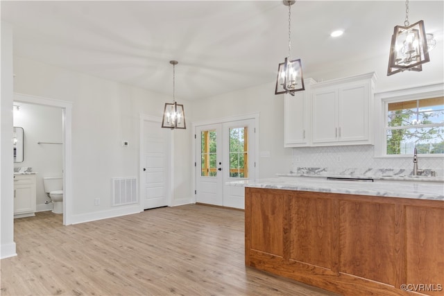 kitchen with light stone counters, light hardwood / wood-style floors, white cabinetry, and sink