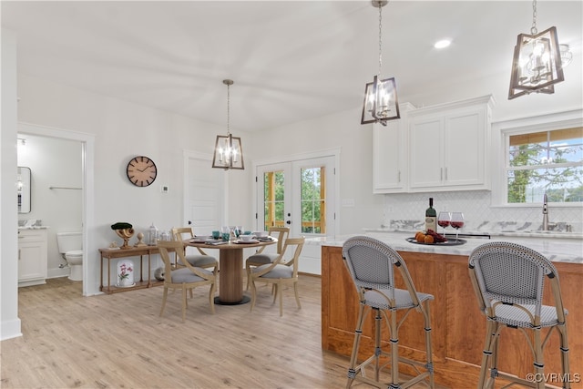 kitchen featuring light wood-type flooring, a healthy amount of sunlight, white cabinetry, and sink