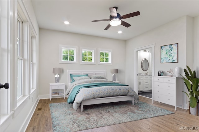 bedroom with ensuite bath, light hardwood / wood-style flooring, and ceiling fan