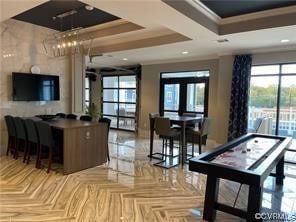 interior space with a tray ceiling, light parquet flooring, a chandelier, and french doors