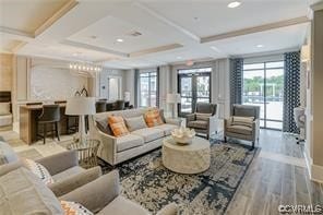 living room with coffered ceiling, ornamental molding, and light wood-type flooring