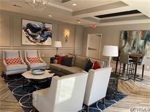 home theater featuring a raised ceiling, ornamental molding, parquet floors, and a chandelier