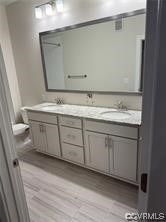 bathroom with double sink vanity, toilet, and hardwood / wood-style floors