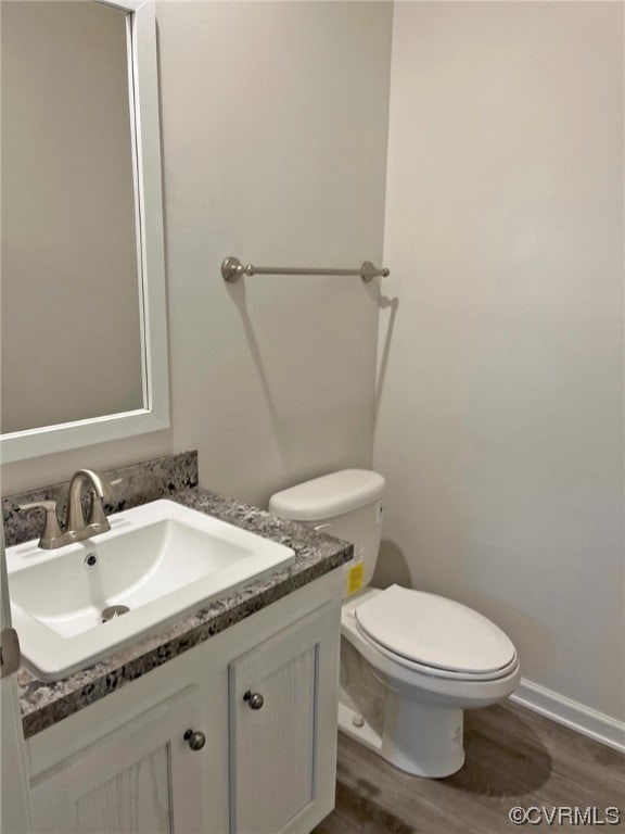 bathroom with toilet, wood finished floors, and vanity