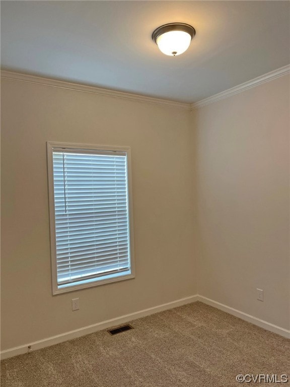 carpeted spare room featuring visible vents, baseboards, and crown molding