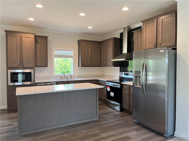 kitchen with a kitchen island, ornamental molding, appliances with stainless steel finishes, wall chimney exhaust hood, and a sink