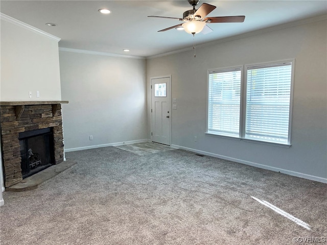 unfurnished living room featuring carpet floors, crown molding, a stone fireplace, and ceiling fan