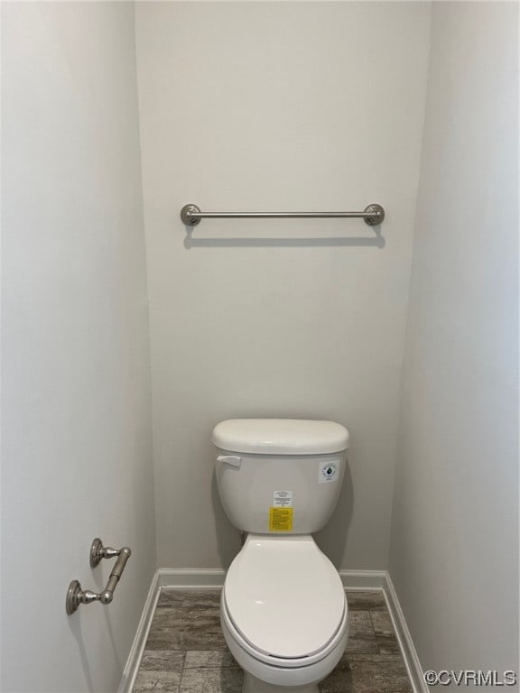 bathroom with baseboards, toilet, and wood finished floors