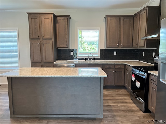 kitchen featuring dark hardwood / wood-style floors, tasteful backsplash, sink, electric stove, and a center island