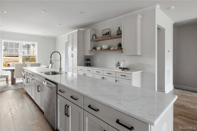 kitchen featuring stainless steel dishwasher, light stone counters, an island with sink, sink, and hardwood / wood-style flooring