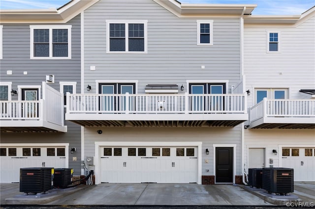 rear view of house featuring a balcony, central AC, and a garage