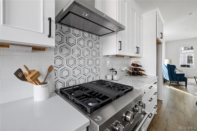 kitchen with tasteful backsplash, dark hardwood / wood-style floors, stainless steel range, light stone countertops, and wall chimney range hood