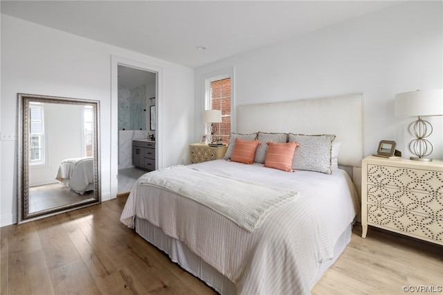 bedroom featuring ensuite bath and light wood-type flooring